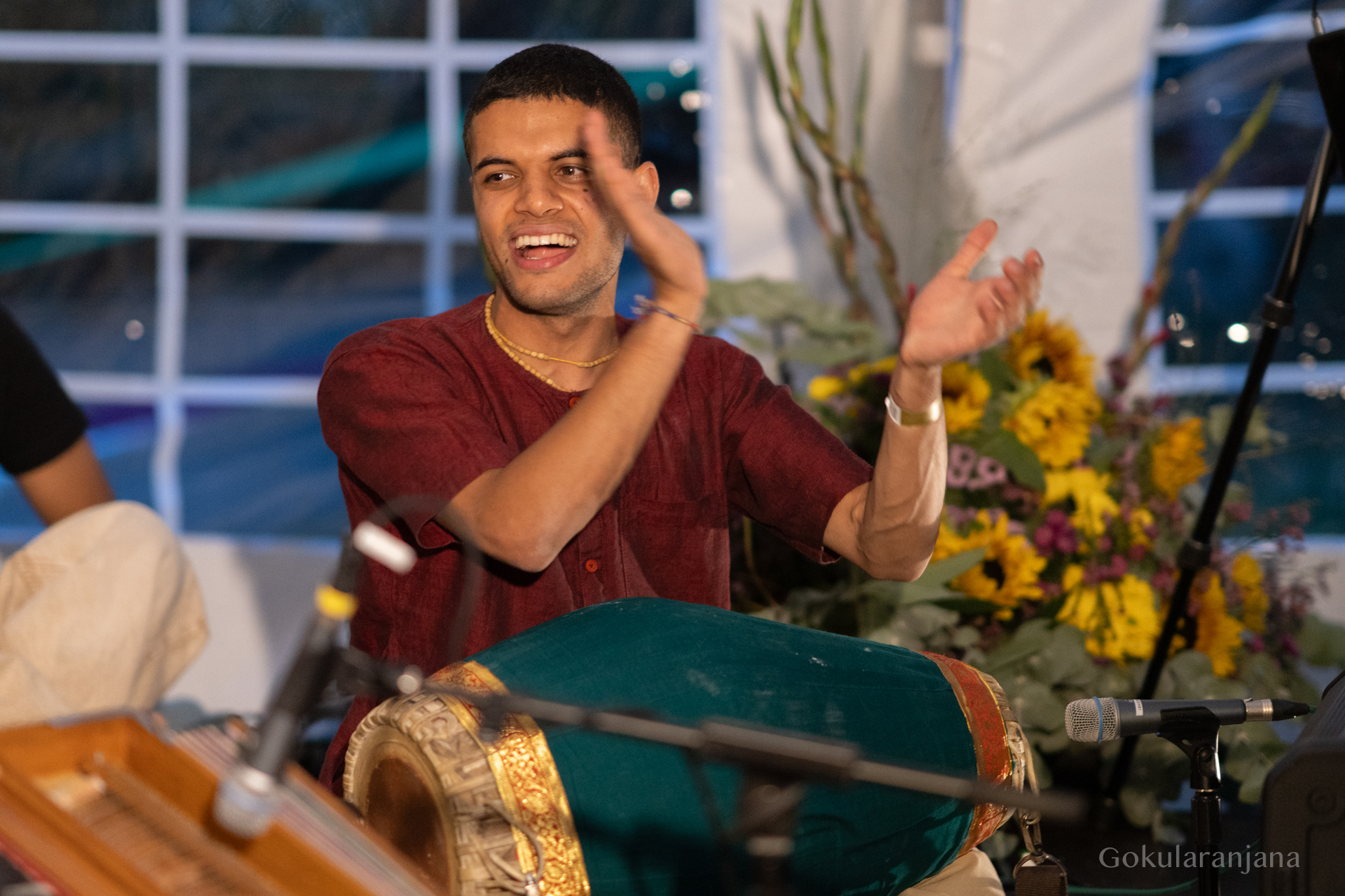 Ein Musiker spielt voller Freude Mṛdaṅga beim Kirtan