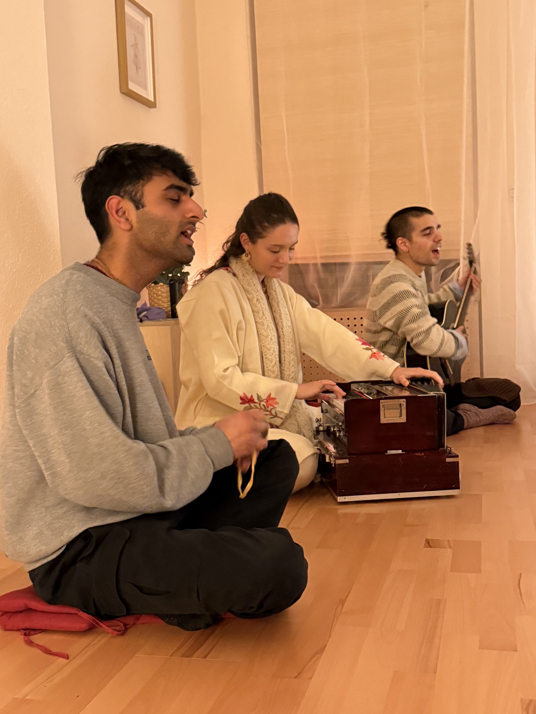 Musikerinnen und Musiker singen bei der Kirtan Lounge mit Harmonium und Gitarre