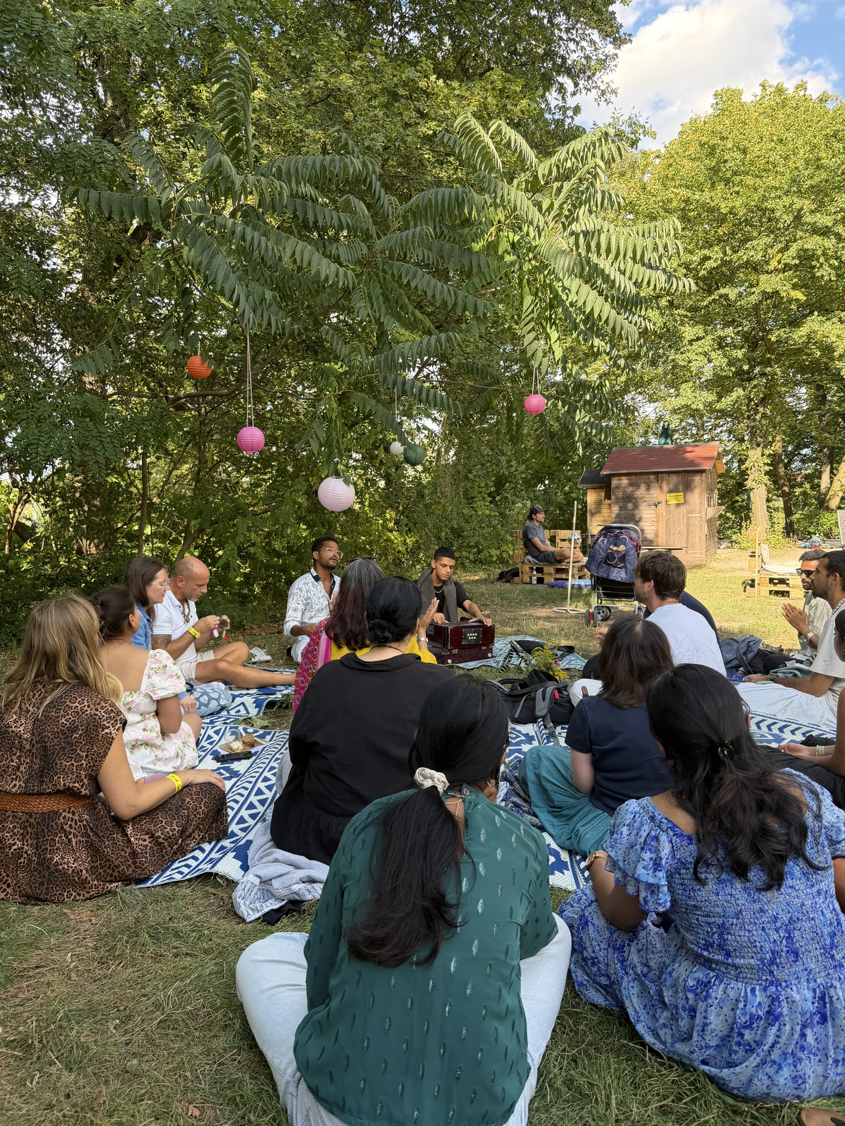 Eine Kirtan-Runde sitzt gemeinsam auf Decken im Park